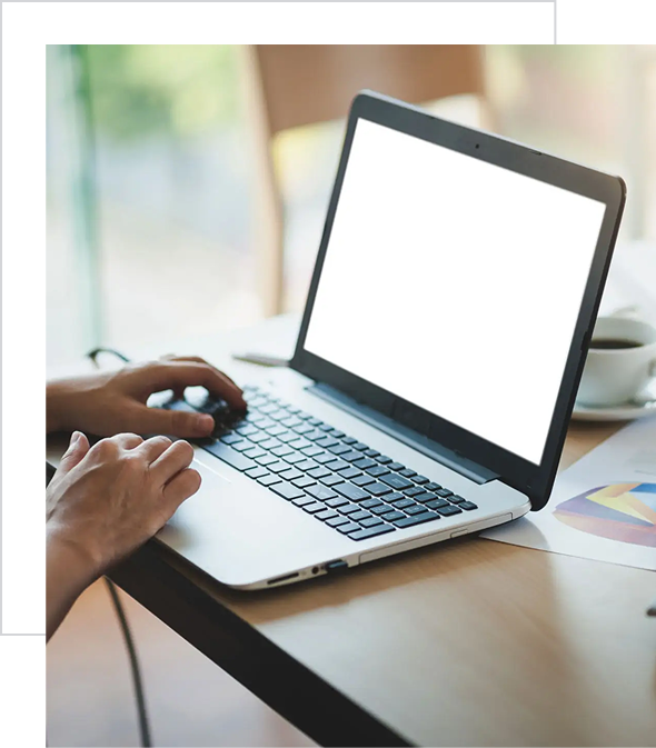 Person typing on a laptop with a blank screen in a bright workspace.