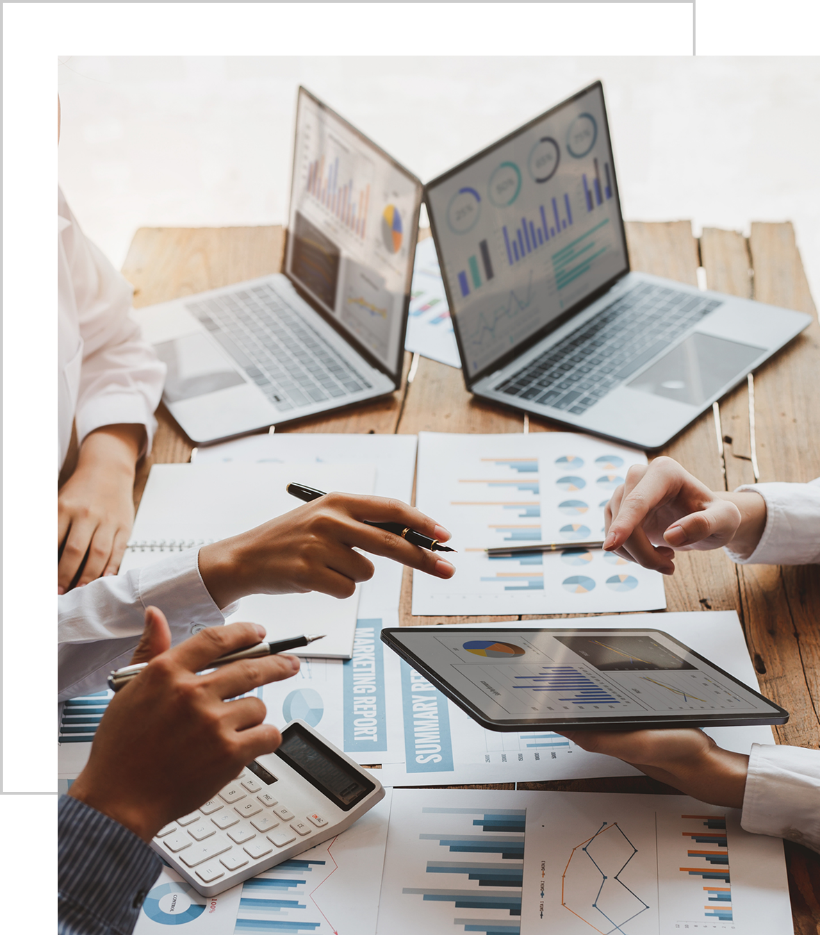 People analyzing financial data on laptops and tablets during a business meeting.