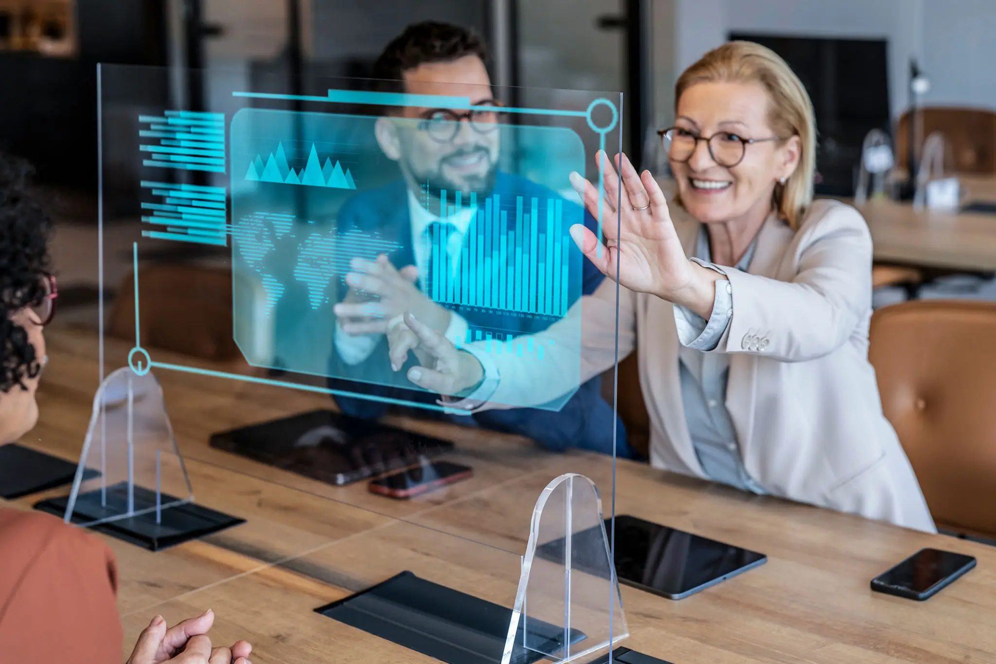 Two colleagues interact with a futuristic holographic display at work.