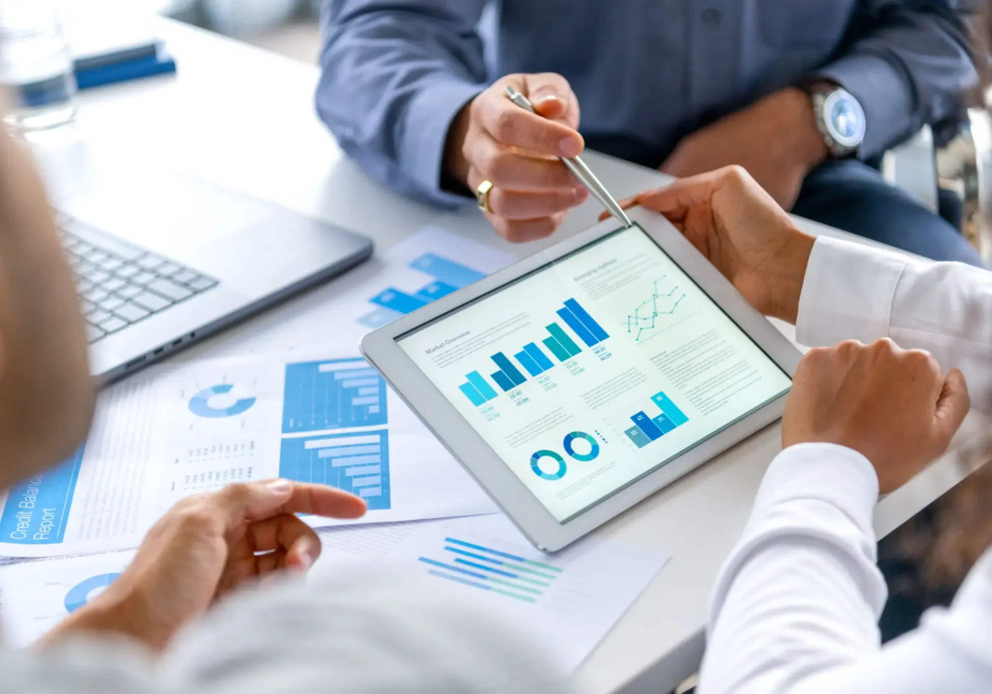 Business professionals analyzing financial data on a tablet during a meeting.