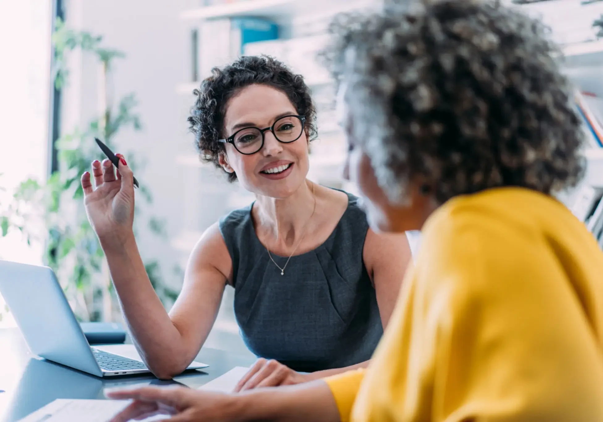 Two women having a friendly conversation in a bright office.
